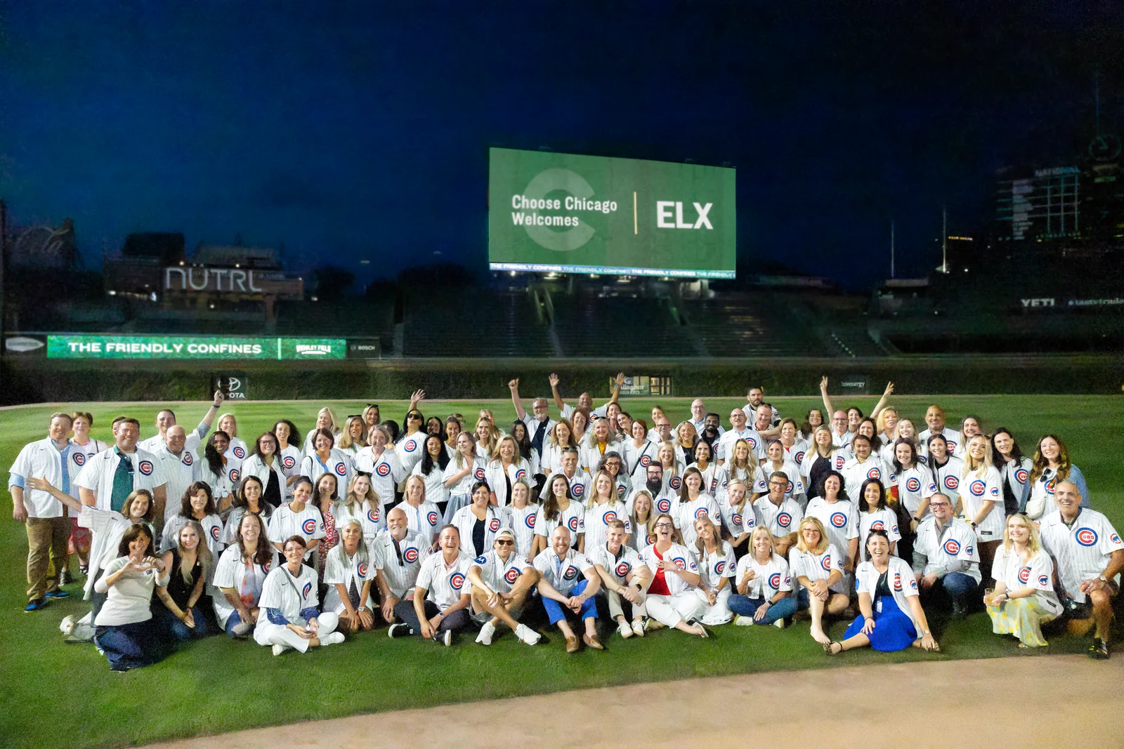 The ELX Congress 2025 group photo at Wrigley Field, Chicago - attendees in Cubs jerseys under a scoreboard reading "Choose Chicago Welcomes ELX"